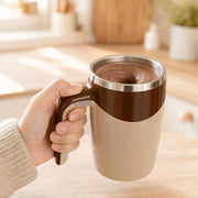 Hand holding the cream & coffee mug while the cocoa stirs itself